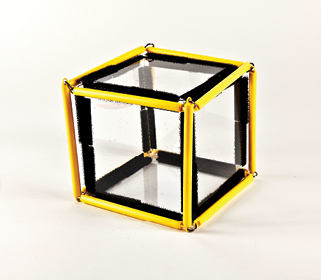 Photo shows a square prism (cube) constructed from Geometro tiles with the corresponding rod model placed over it, in 3-D, in Position 2. That is, slightly rotated clockwise from the starting, face-on position (viewed from the right).