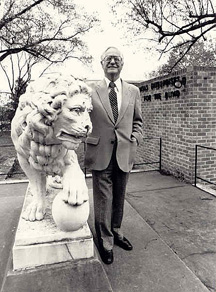 Roy Kumpe stands with the historic Lion statue that guards the Lions World Services for the Blind (LWSB) campus. at the corner of 28th Street