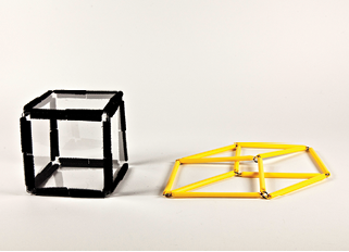 Photo shows a square prism (cube) constructed from Geometro tiles, in 3-D, Position 2, standing beside the corresponding rod model now in 2-D.