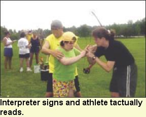 Interpreter signs and athlete tactually reads, Photo submitted by Camp Abilities.