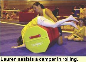 Lauren helps a camper, who is lying prone over an octagon tumbler, to roll forward. Photo submitted by Camp Abilities.