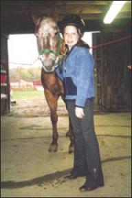 Quinn stands next to her horse, holding the bridle.