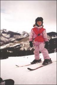 Megan on her skis, standing on a snow-covered mountain top.