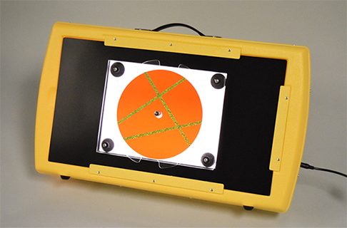 Photograph of the APH Light Box demonstrating the use of the rectangular blackout sheet from the Level 1 Light Box Materials with the APH Plexiglas® Spinner, and a red overlay modified with yellow holographic sticker strips.