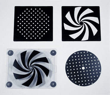 Photograph of APH Plexiglas® Spinner and three black and clear patterned overlays: black overlay with an octagon pattern of clear dots; black overlay with a black and clear pinwheel pattern; black overlay with clear dot pattern.