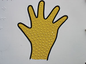 A raised outline of a hand, filled with a dotted areal pattern, embossed in paper.