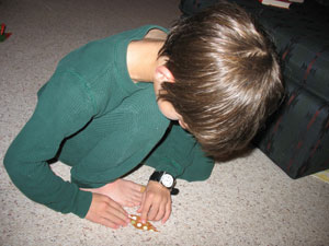 Older child carefully traces the edge of a small object with the fingers of his right hand as his left hand marks the starting point for his exploration.