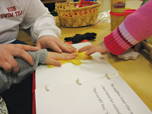 Two children explore a fuzzy cutout in a tactile book.