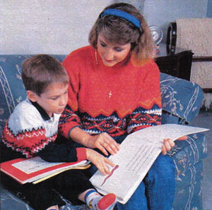 A four-year old uses his fingers to examine a very simple raised line illustration as his caregiver reads aloud.