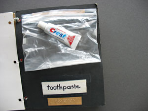 A tube of toothpaste provided as an illustration in a book about bath time; it is enclosed in a plastic zip-lock bag stapled to the poster board page.