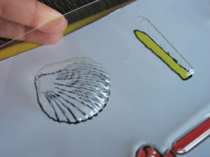 A thermoformed image of a shell in clear plastic; beneath the thermoform is a print drawing of the shell provided for visual learners.