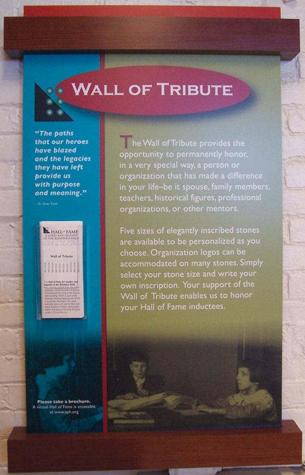 Panel describes the Wall of Tribute. Visitors are invited to take a pamphlet, in print or braille, explaining how to honor a mentor, friend, organization, or family member
