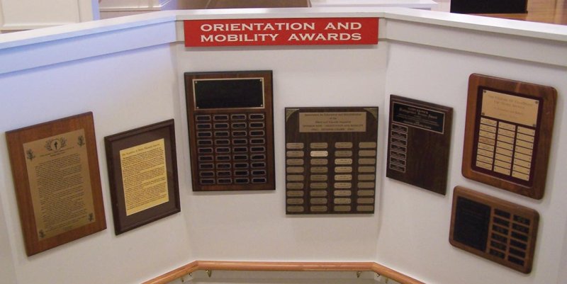 Award Plaques of the AER Orientation and Mobility Division on open stairwell connecting the Hall of Fame with the APH Museum