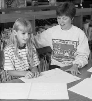 Young girl reading braille with her teacher