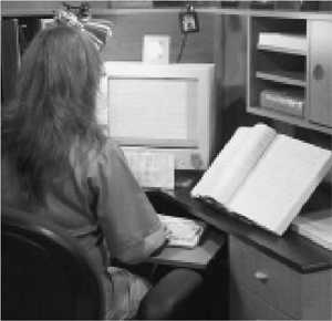 A woman using a computer to transcribe braille.