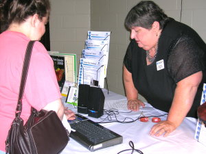 APH's Elaine Kitchel shows the Braille+, Refreshabrille 18, and the Qwerty Docking Station to a conference attendee