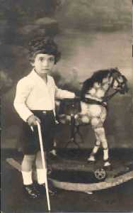 Boy with white cane poses beside rocking horse