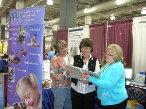 Diane Pevsner and Mary Jean Sanspree, of the University of Alabama at Birmingham, review a new product with APH's Cindy Amback at the exhibit booth.