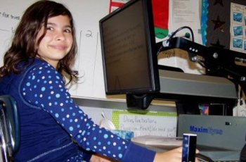 Emily Eagle smiles as she tries out her new MaximEyes Video Magnifier. Emily is a 5th grade student in Texas.