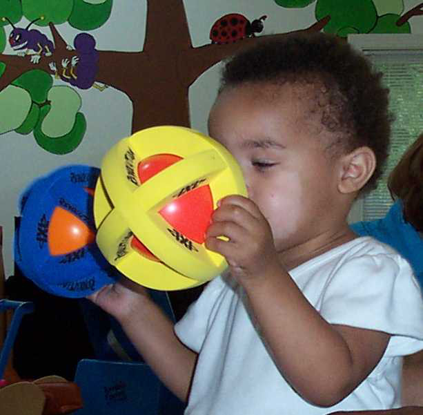 small child holding two IXL RevolutionTM Sport Balls