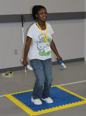 A teen jumps rope using a ropeless jump rope; she is on an anti shock orientation mat. 