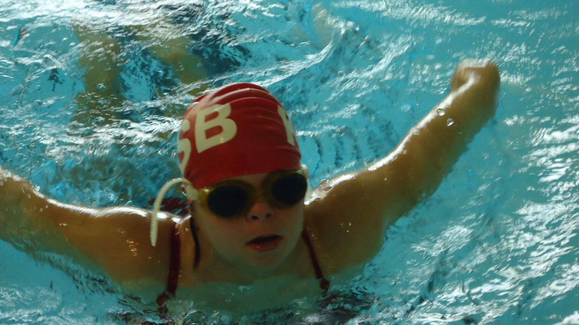 A girl swims butterfly stroke.