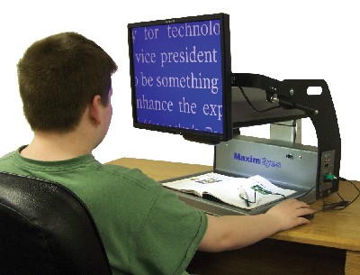 Photo of a young man seated in front of a MaximEyes Video Magnifier